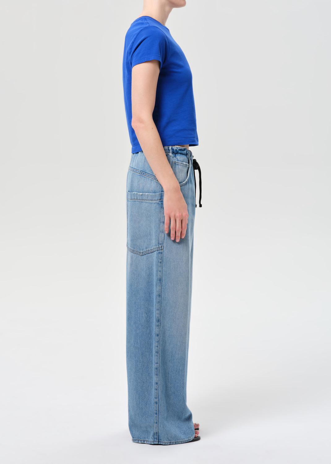 Person wearing a blue t-shirt and light blue jeans on a white background