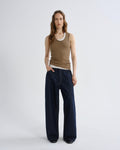 Woman wearing a brown tank top and dark blue wide-leg pants on a white background