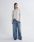 Person wearing a white top and blue jeans on a white background