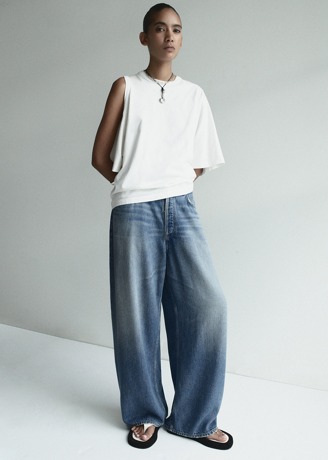 Person wearing a white top and blue jeans against a plain background
