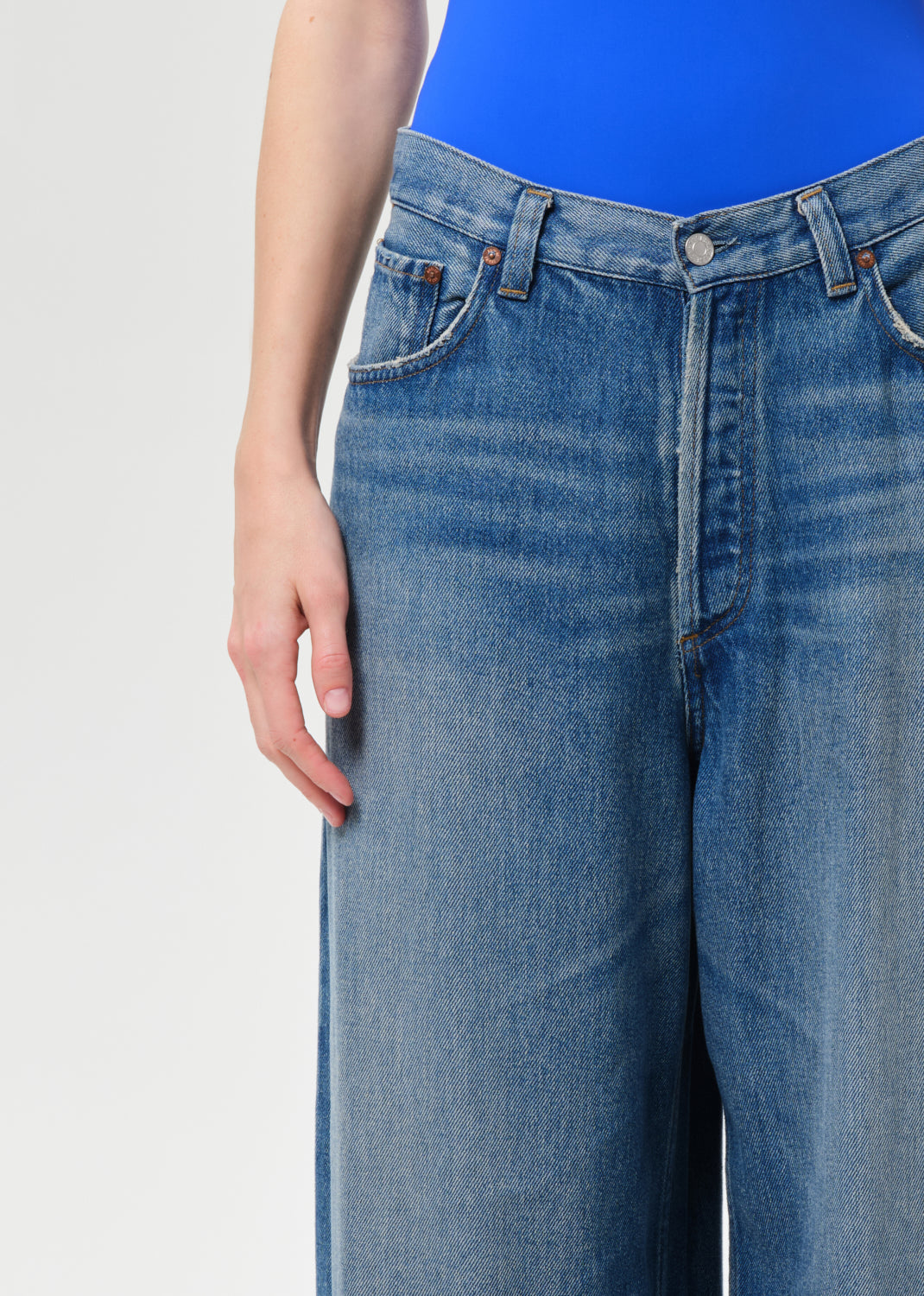 Blue jeans worn by a person on a light gray background