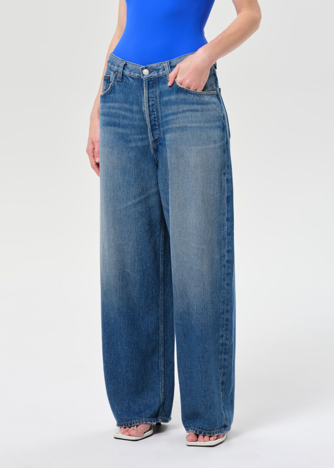 Person wearing blue jeans and a blue top on a white background