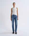 Person wearing a white sleeveless top and blue jeans on a white background