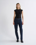 Woman wearing a black cap sleeve top with dark indigo straight leg jeans on a grey background.