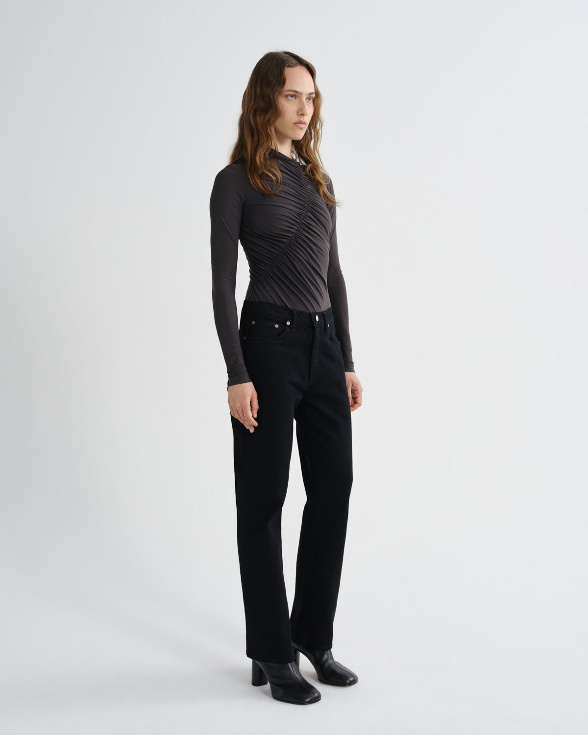 Person wearing a black long-sleeve top and black pants on a white background