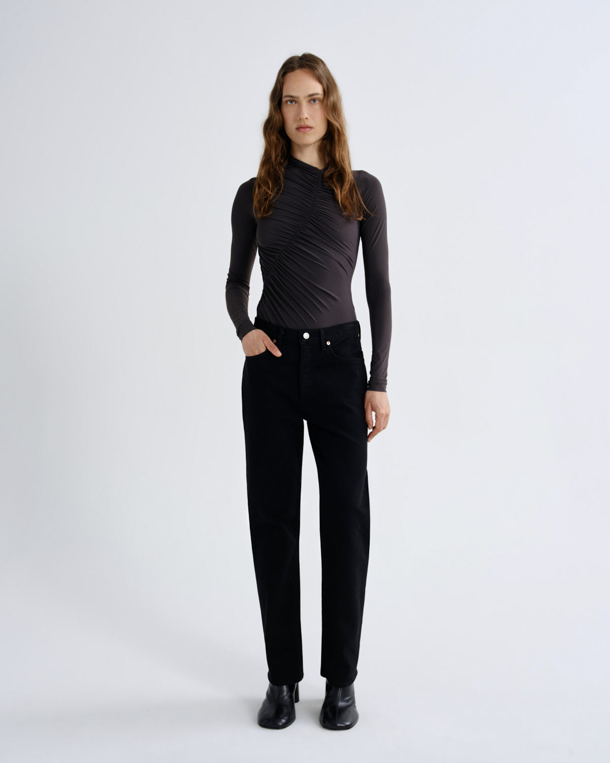 Woman wearing a black long-sleeve top and black pants on a white background