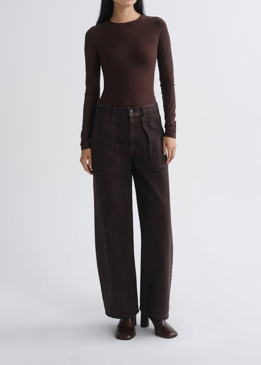 A model wearing a dark brown long-sleeve crewneck top and matching dark brown wide-leg trousers, standing against a grey background.
