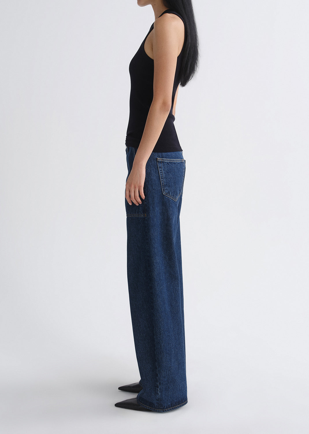 Person wearing blue jeans and a black top on a grey background