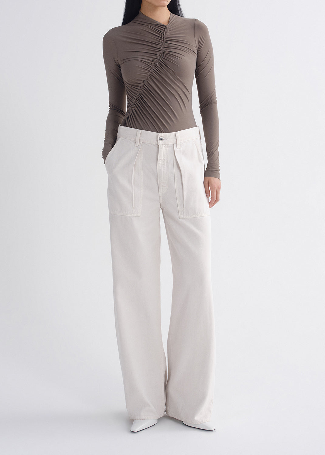 Person wearing a brown ribbed long-sleeve top and light gray wide-leg pants on a grey background