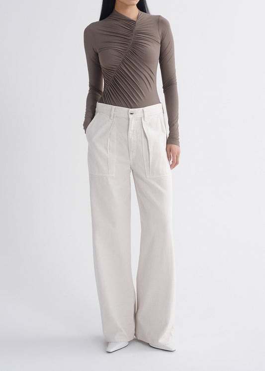 Person wearing a brown ribbed long-sleeve top and light gray wide-leg pants on a grey background