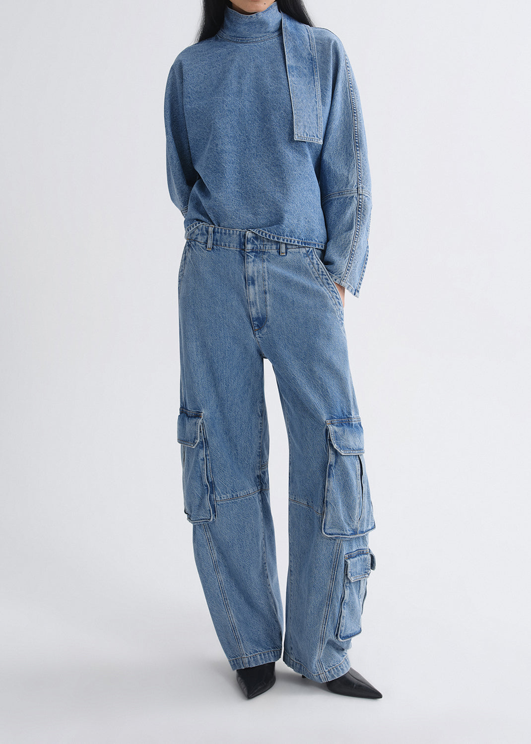Person wearing a blue denim outfit with cargo pants on a grey background