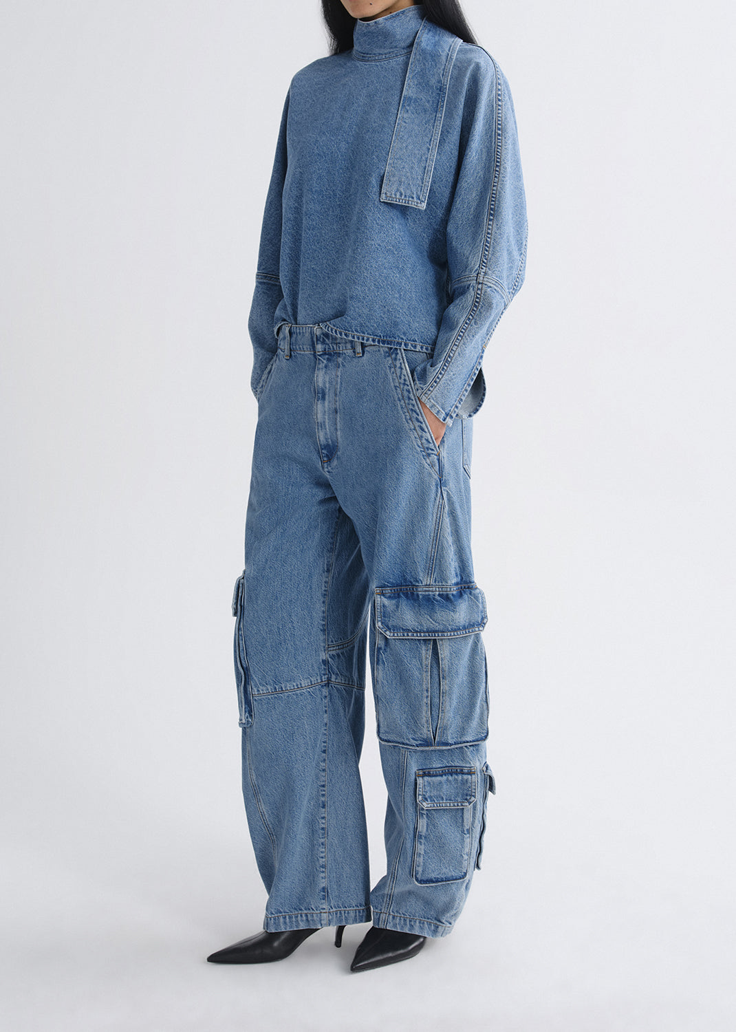 Person wearing a blue denim outfit with cargo pants on a grey background