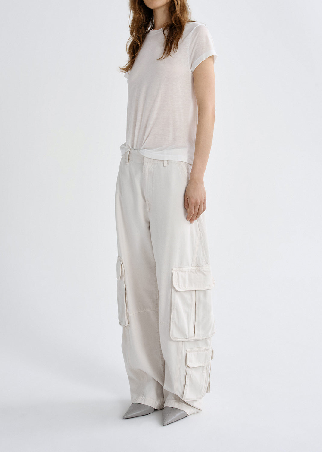 Person wearing a white t-shirt and light-colored cargo pants on a grey background