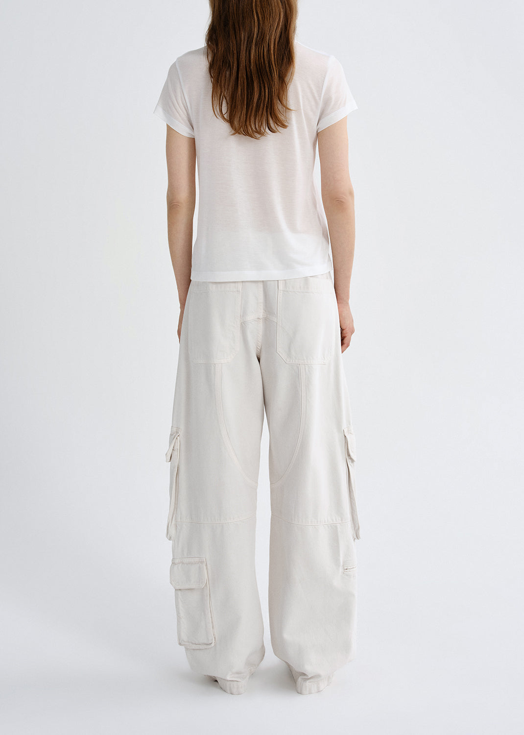 Person wearing a white t-shirt and light-colored cargo pants on a grey background
