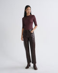 Woman wearing a burgundy top and brown leather pants on a white background