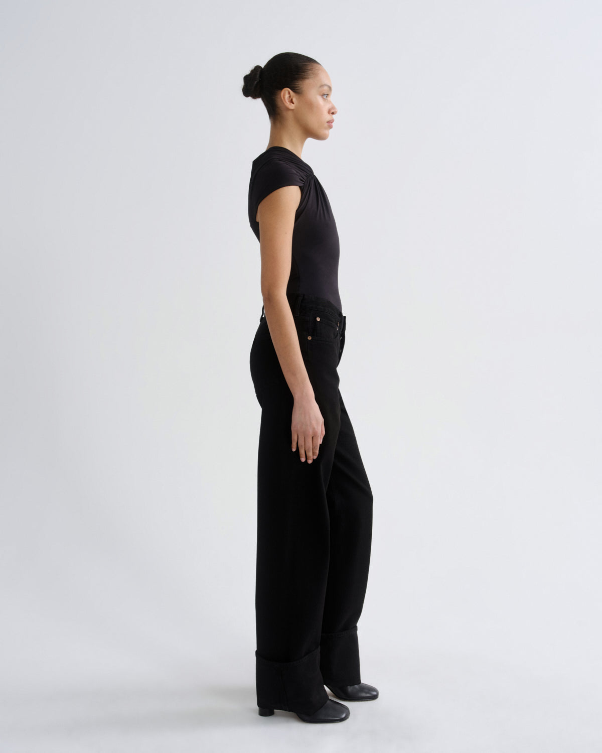 Person wearing a black sleeveless top and wide-leg pants on a white background