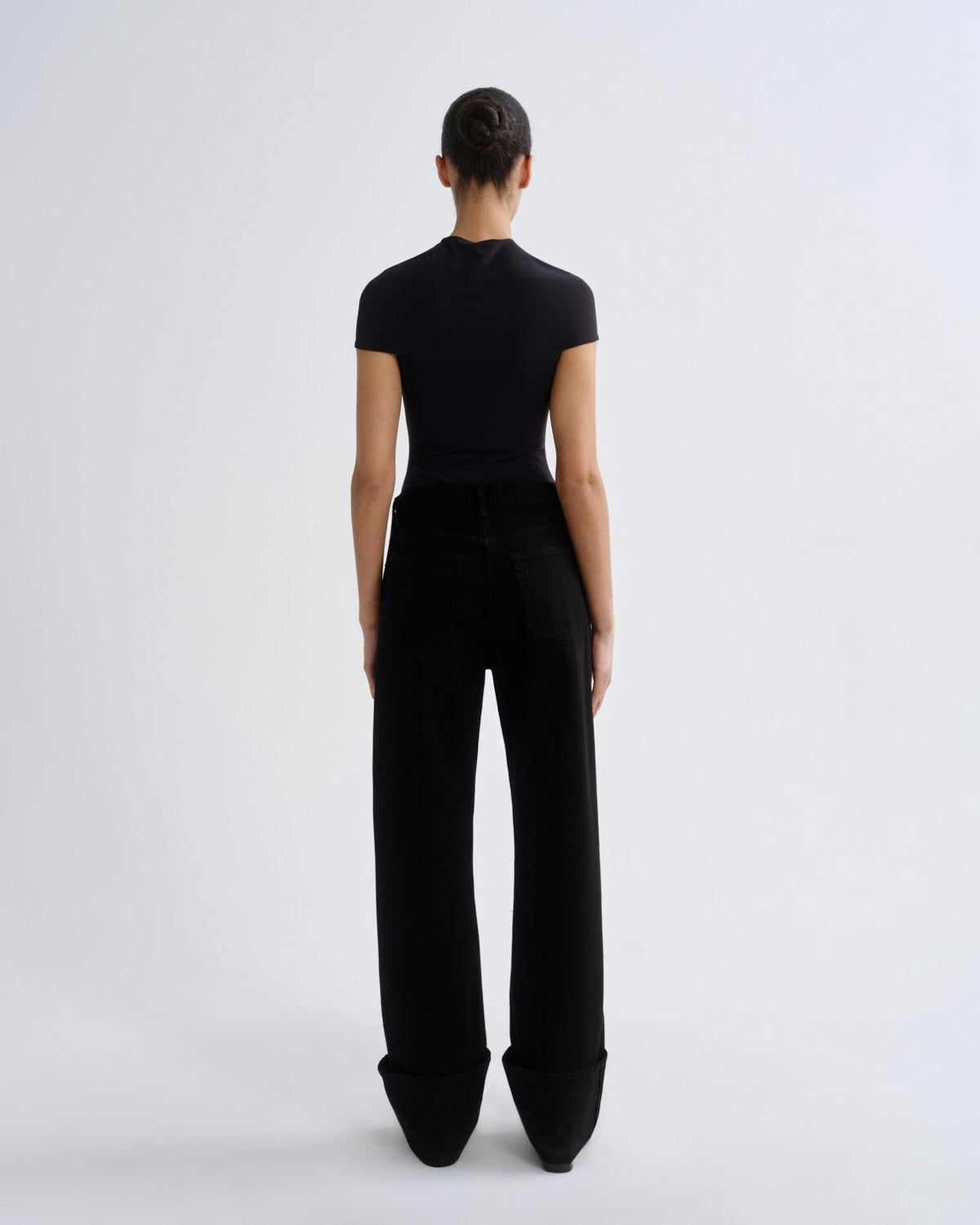Person wearing a black outfit with wide-leg pants on a white background