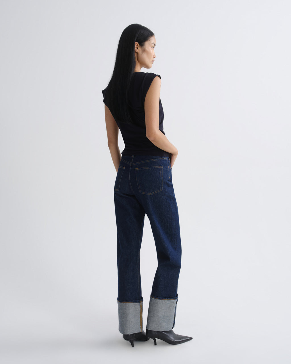 Woman wearing dark blue jeans with a white background