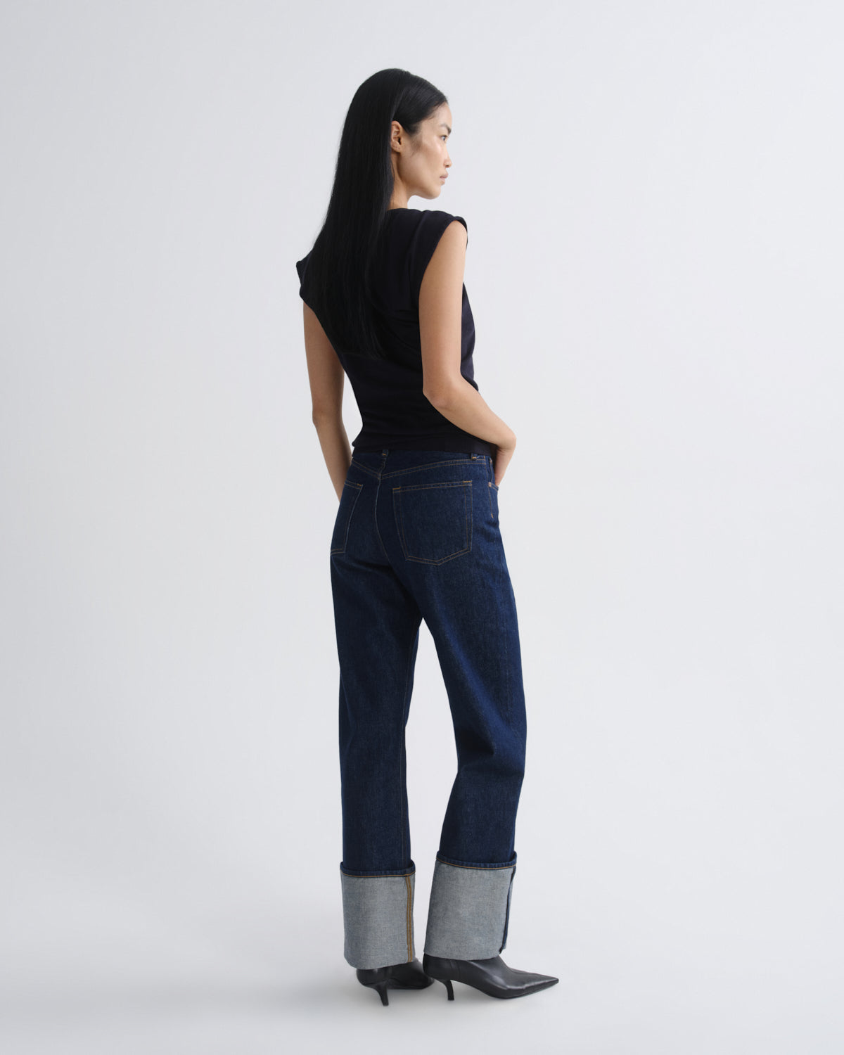 Woman wearing dark blue jeans with a white background