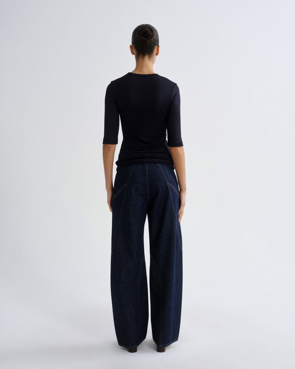 Person wearing blue top and dark blue pants on a grey background