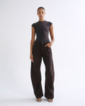 A model stands against a light gray studio background wearing a dark charcoal gray short-sleeve mock-neck top and dark brown wide-leg trousers.