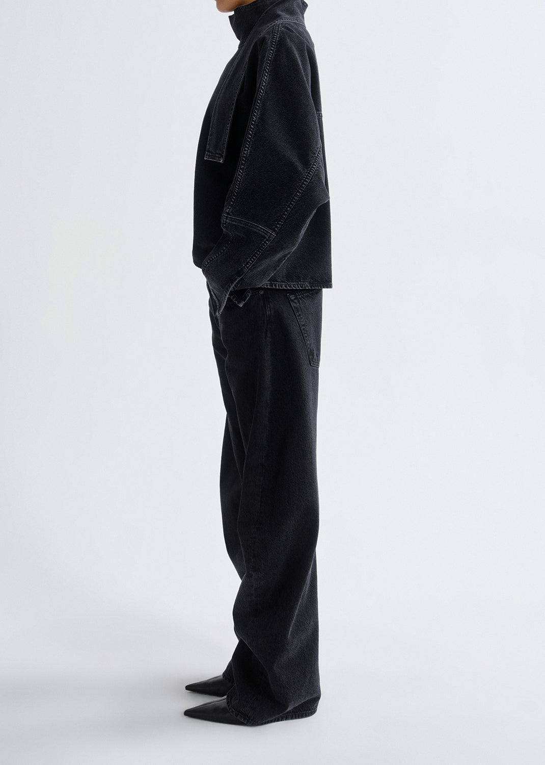 Person wearing a black outfit with wide-leg pants on a grey background
