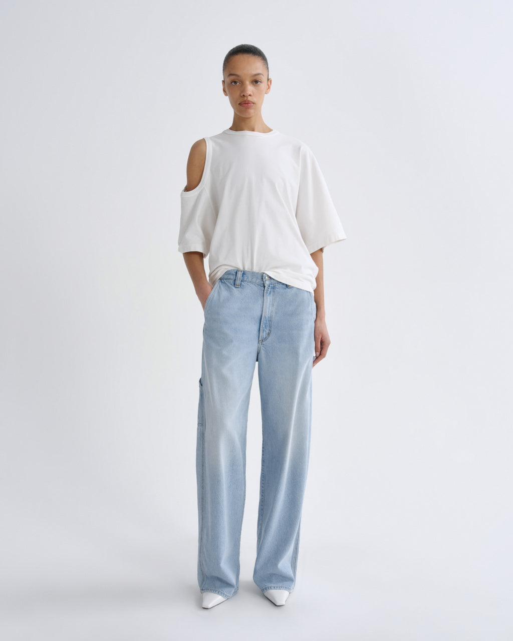 Person wearing a white top and light blue pants on a plain background