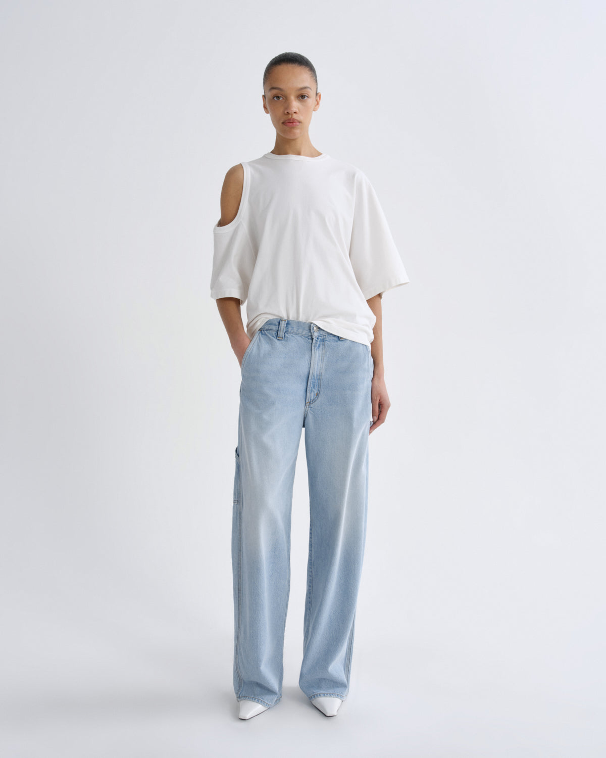 Person wearing a white top and light blue pants on a plain background