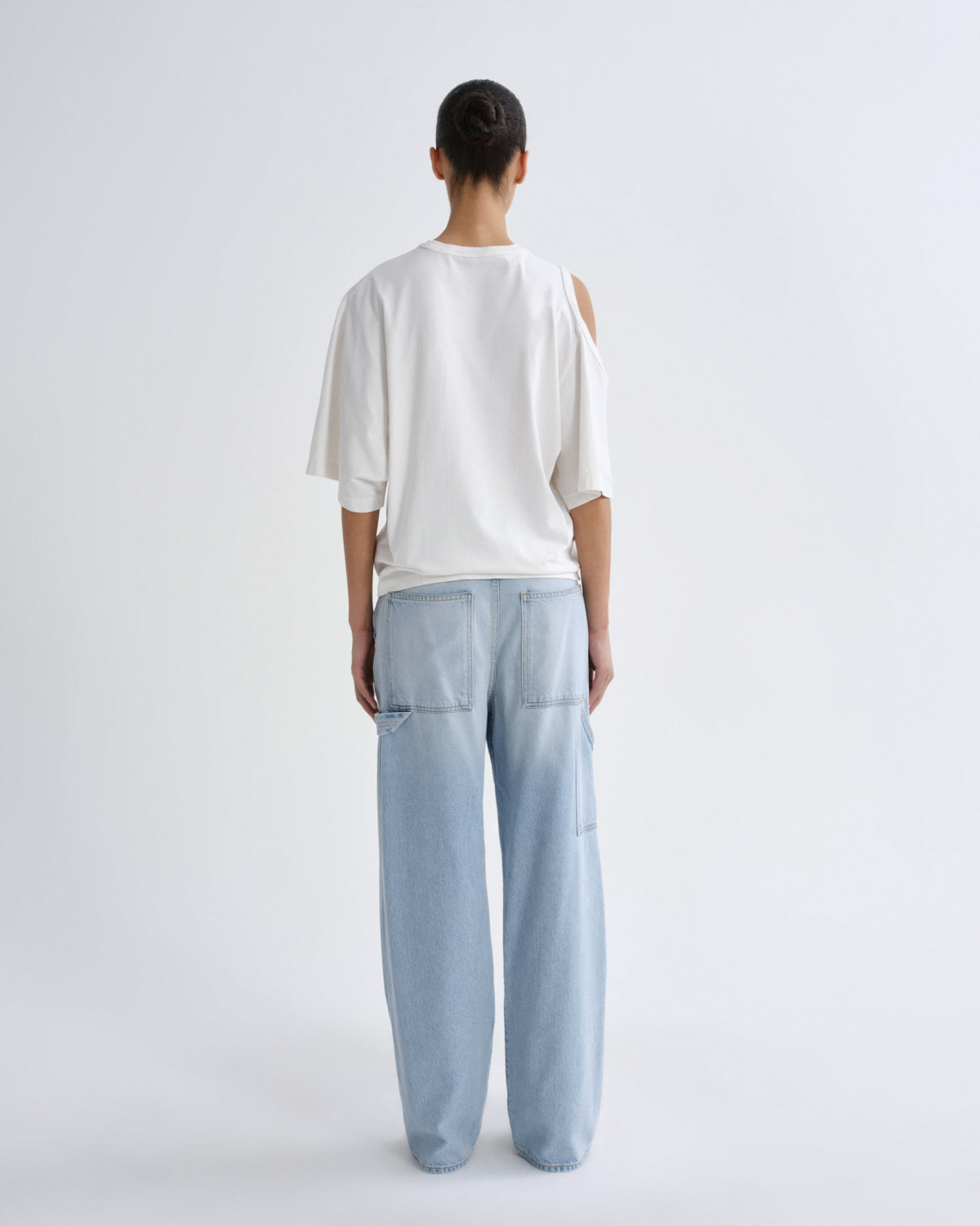 Person wearing a white top and light blue pants on a plain background