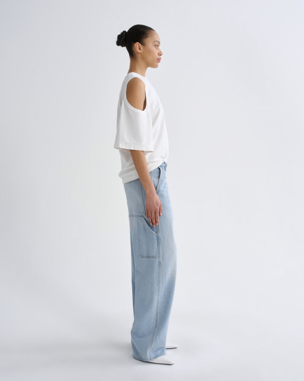 Person wearing a white top and light blue pants on a plain background