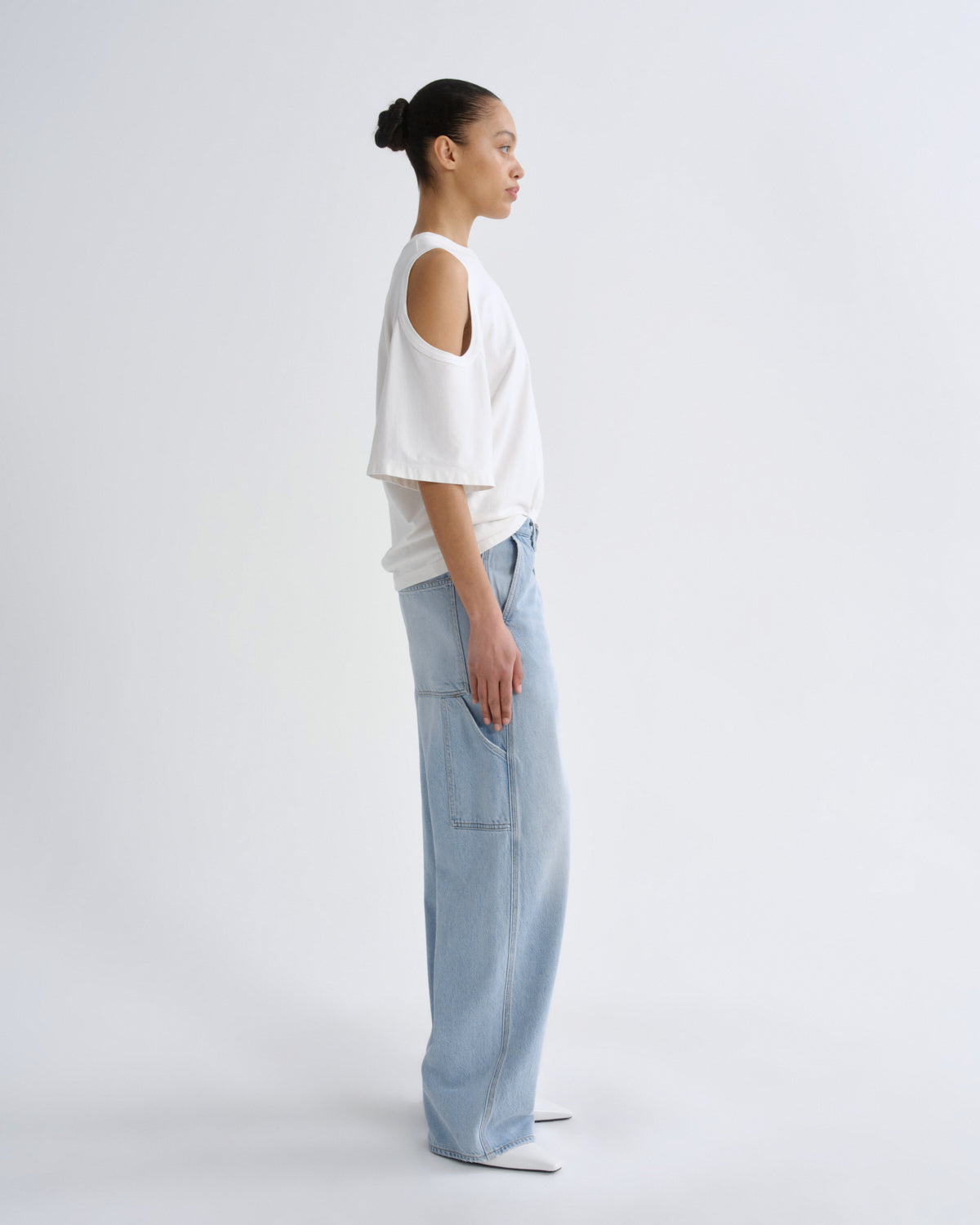 Person wearing a white top and light blue pants on a plain background