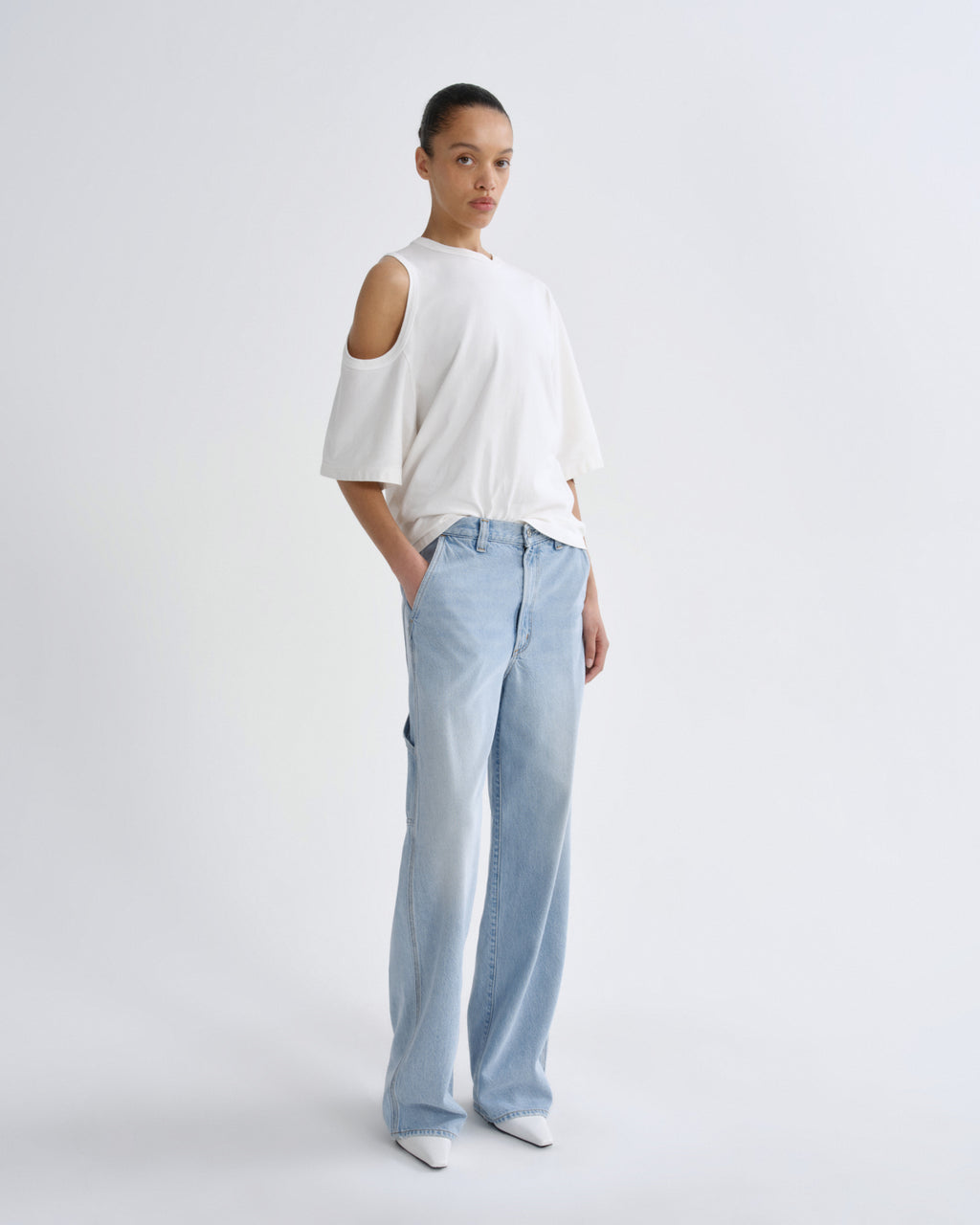 Person wearing a white top and light blue pants on a plain background