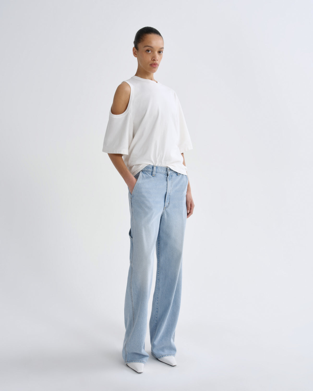 Person wearing a white top and light blue pants on a plain background