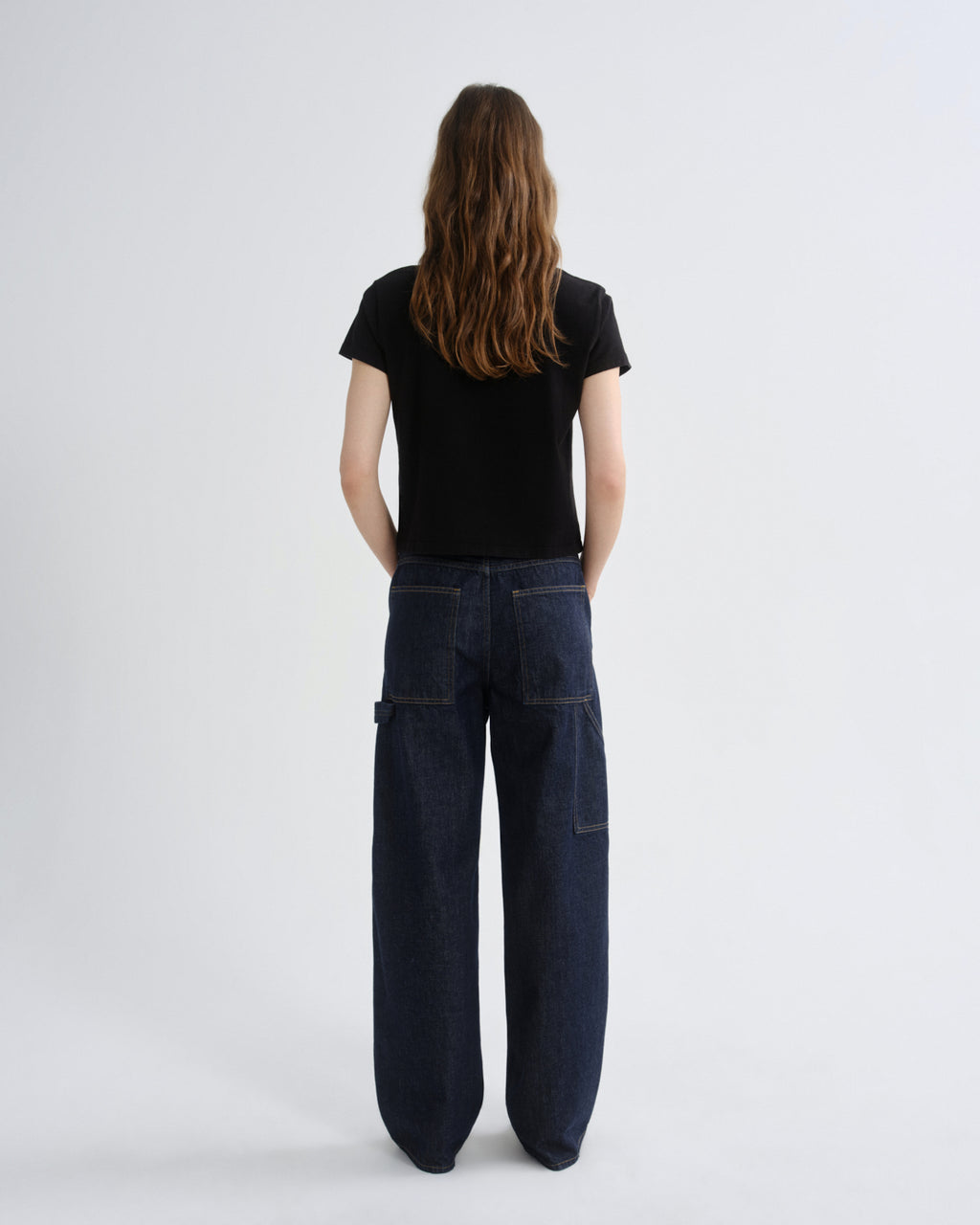 Person wearing dark blue jeans and a black t-shirt on a white background