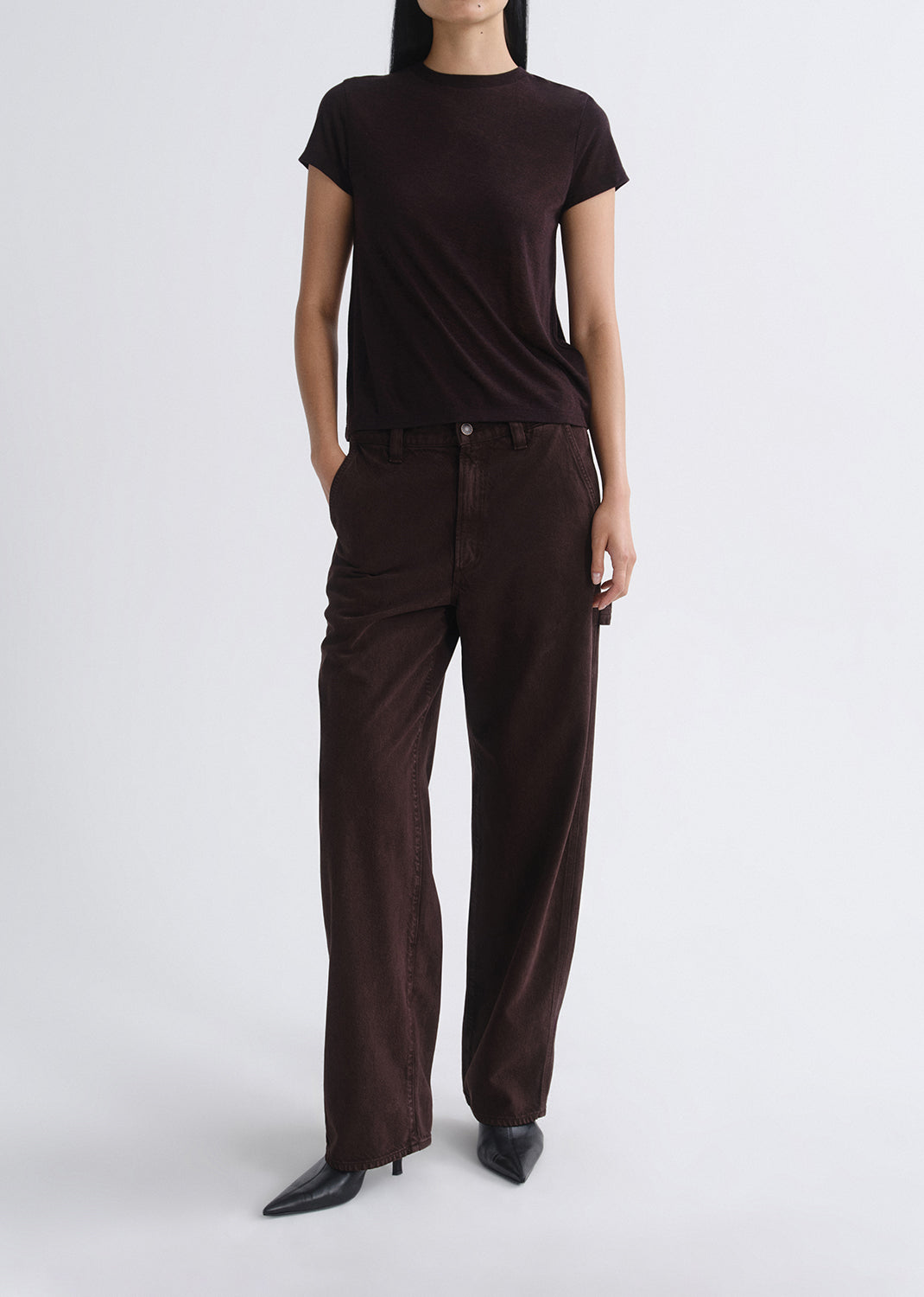 Person wearing a brown t-shirt and wide-leg pants on a grey background