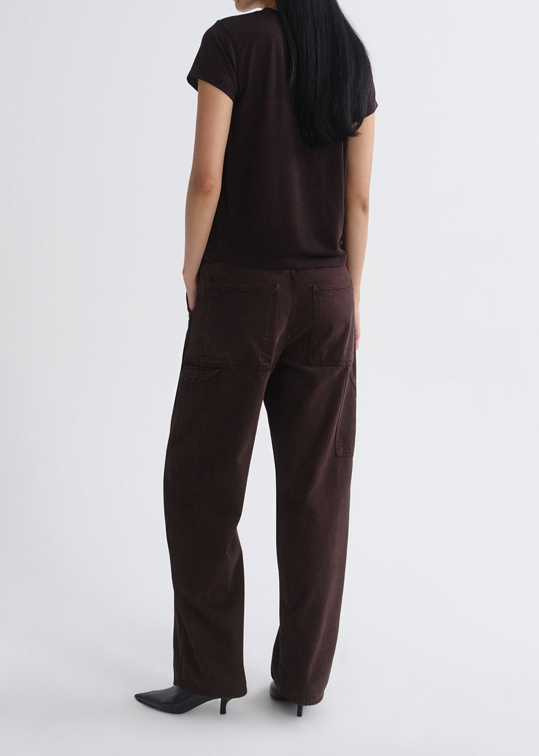Person wearing a brown t-shirt and pants on a grey background