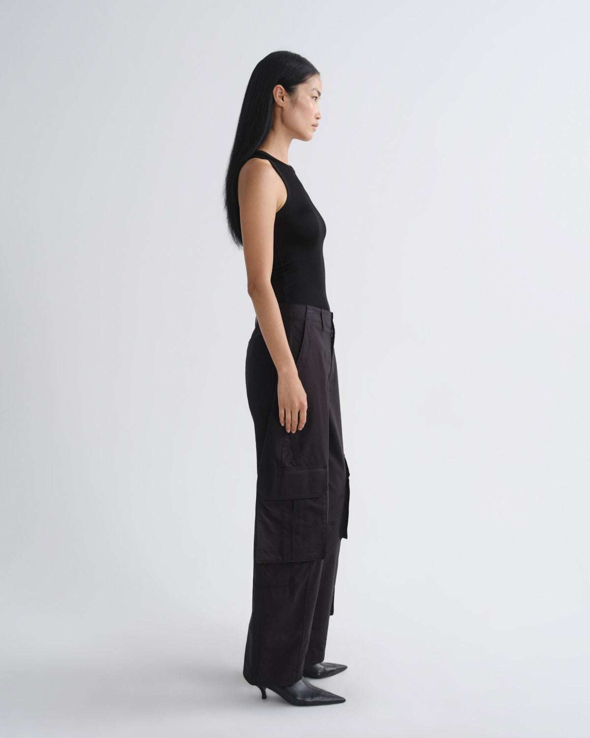 Woman wearing a black sleeveless top and wide-leg pants on a white background
