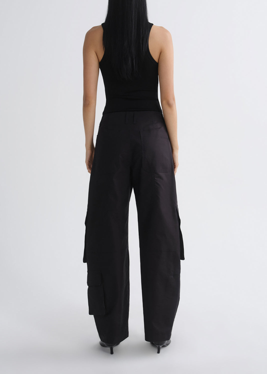 A model shown from the back wearing black wide-leg cargo pants and a black sleeveless top against a grey background.