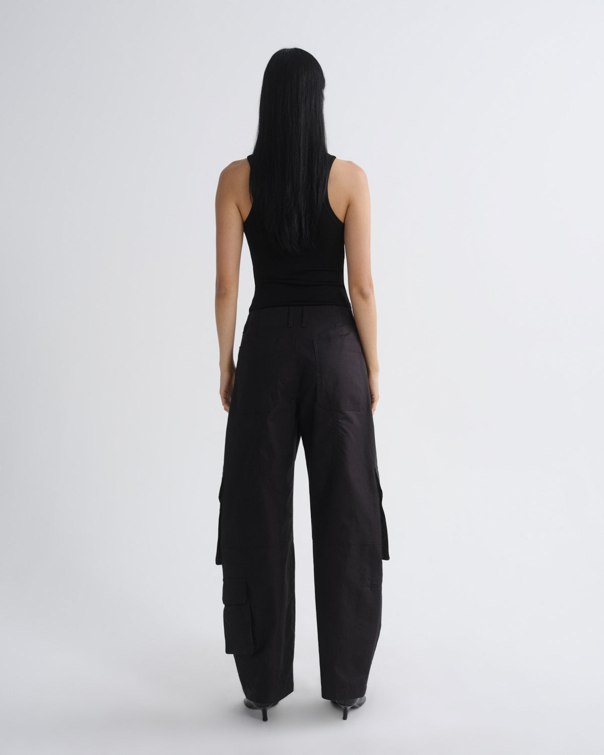 Person wearing a black sleeveless top and wide-leg pants on a white background