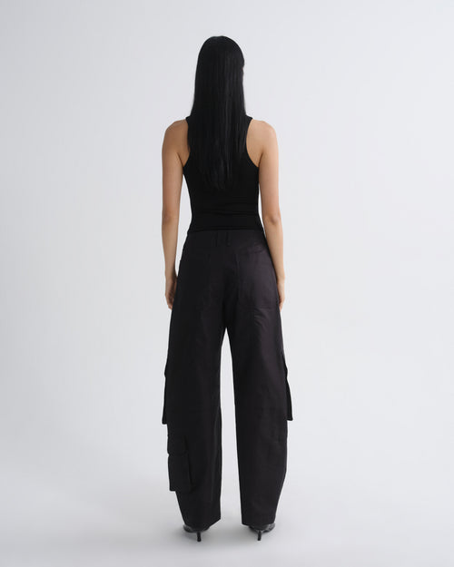 Person wearing a black sleeveless top and wide-leg pants on a white background