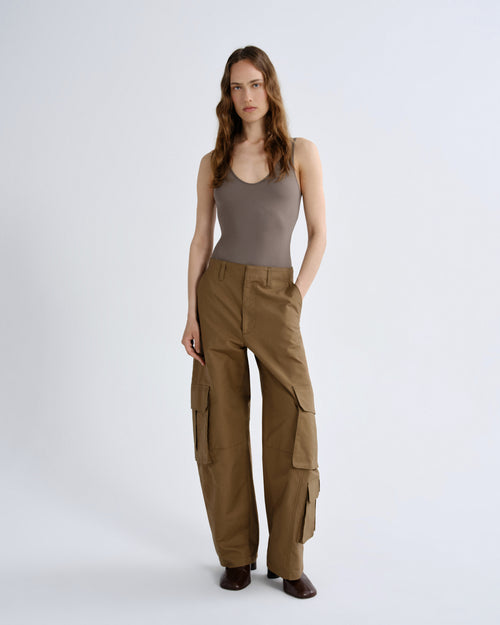 Woman wearing a brown tank top and cargo pants on a white background