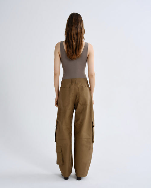 Woman wearing a sleeveless top and brown cargo pants on a white background