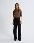 Woman wearing a brown top and black pants on a white background
