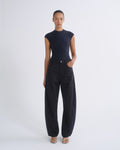 A model stands against a light gray studio background wearing a dark navy sleeveless mock-neck top and matching dark navy wide-leg pants.