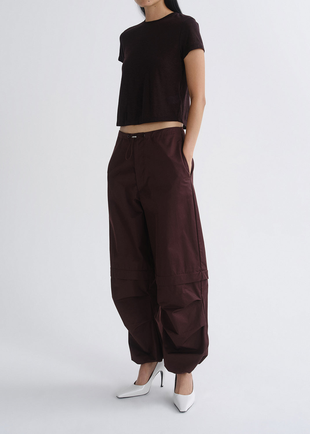 Person wearing a brown outfit with wide-leg pants on a grey background