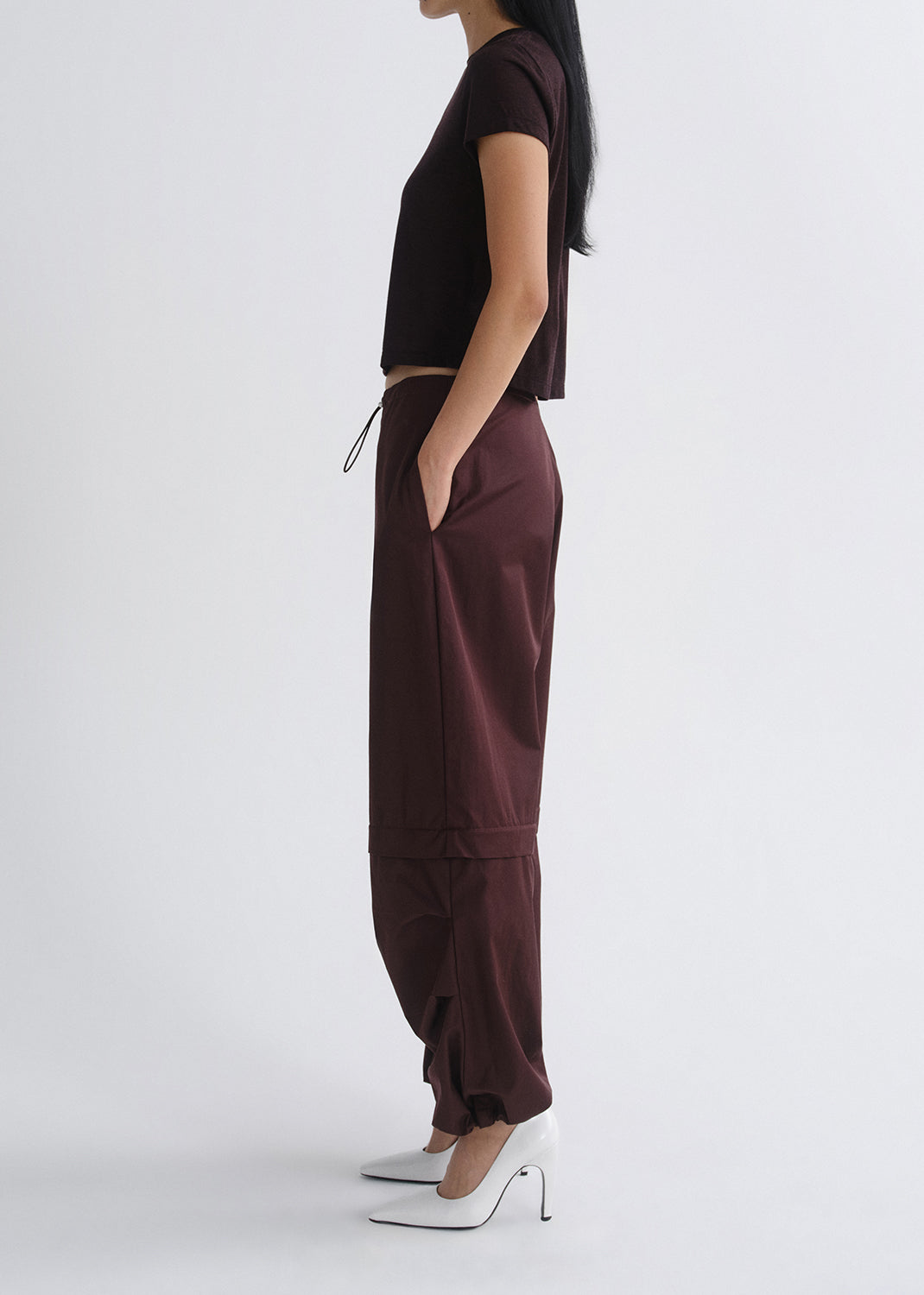 Person wearing a black top and maroon pants on a grey background