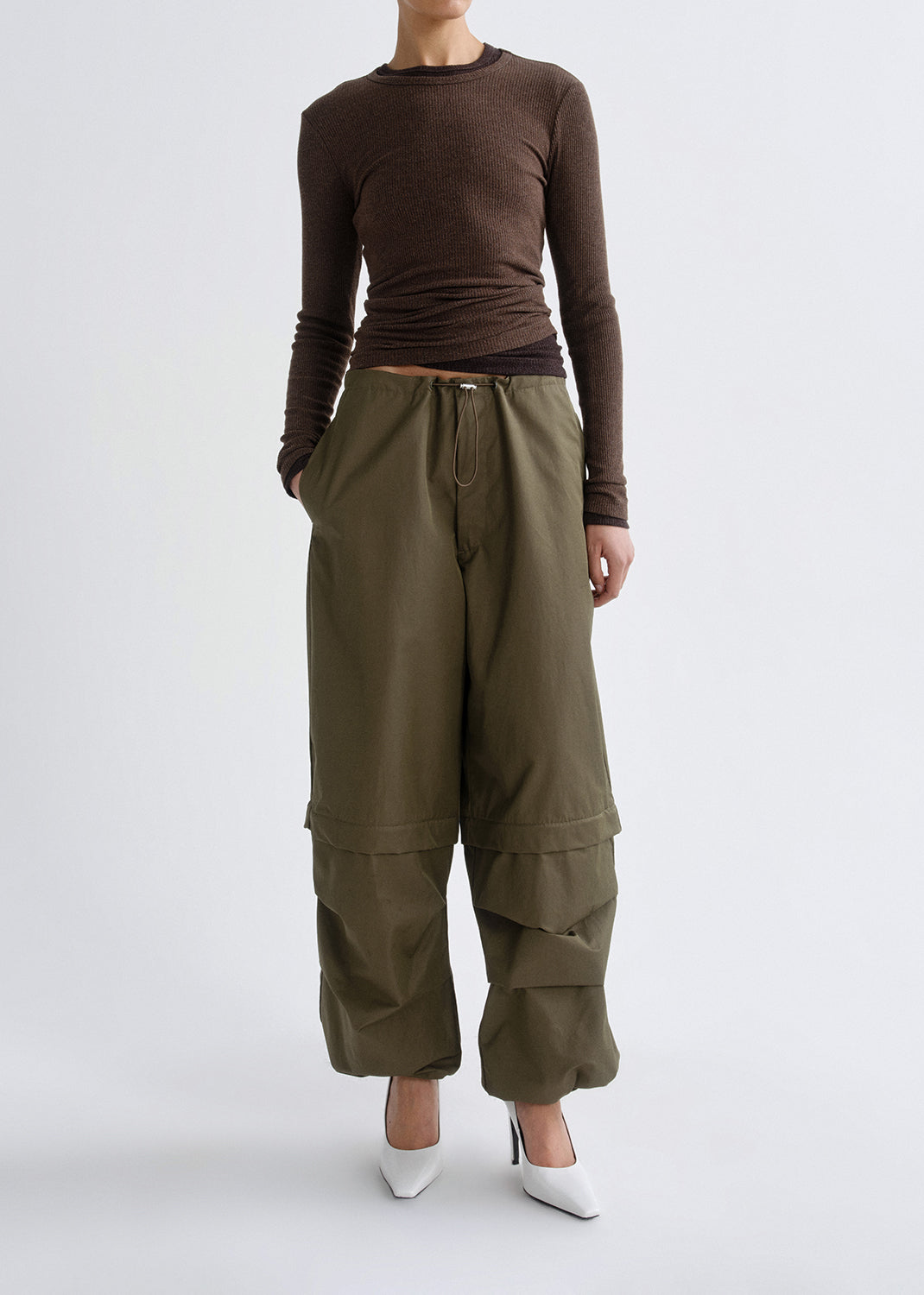 Person wearing a brown long-sleeve top and olive green wide-leg pants on a grey background