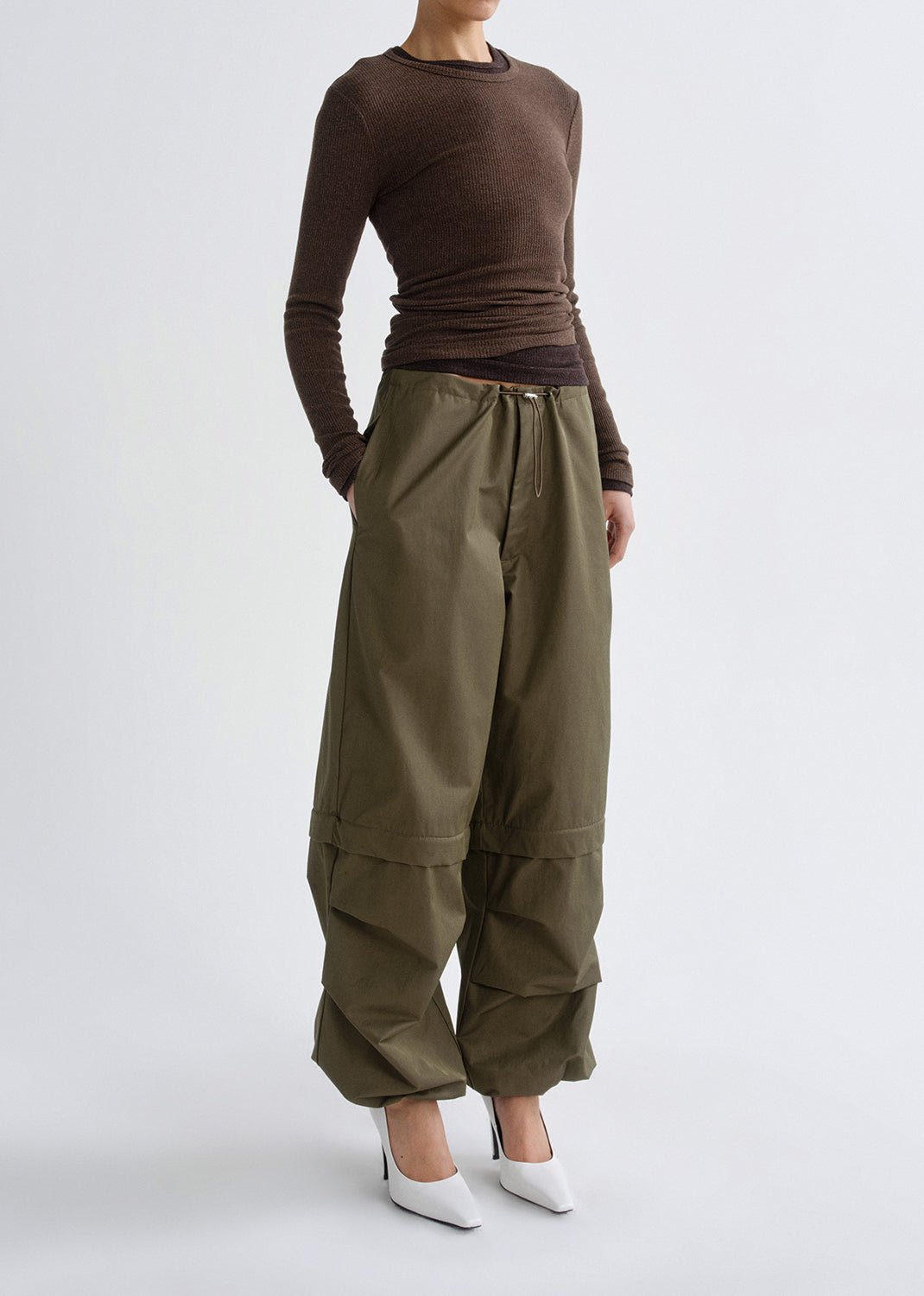 Person wearing a brown long-sleeve top and olive green wide-leg pants on a grey background