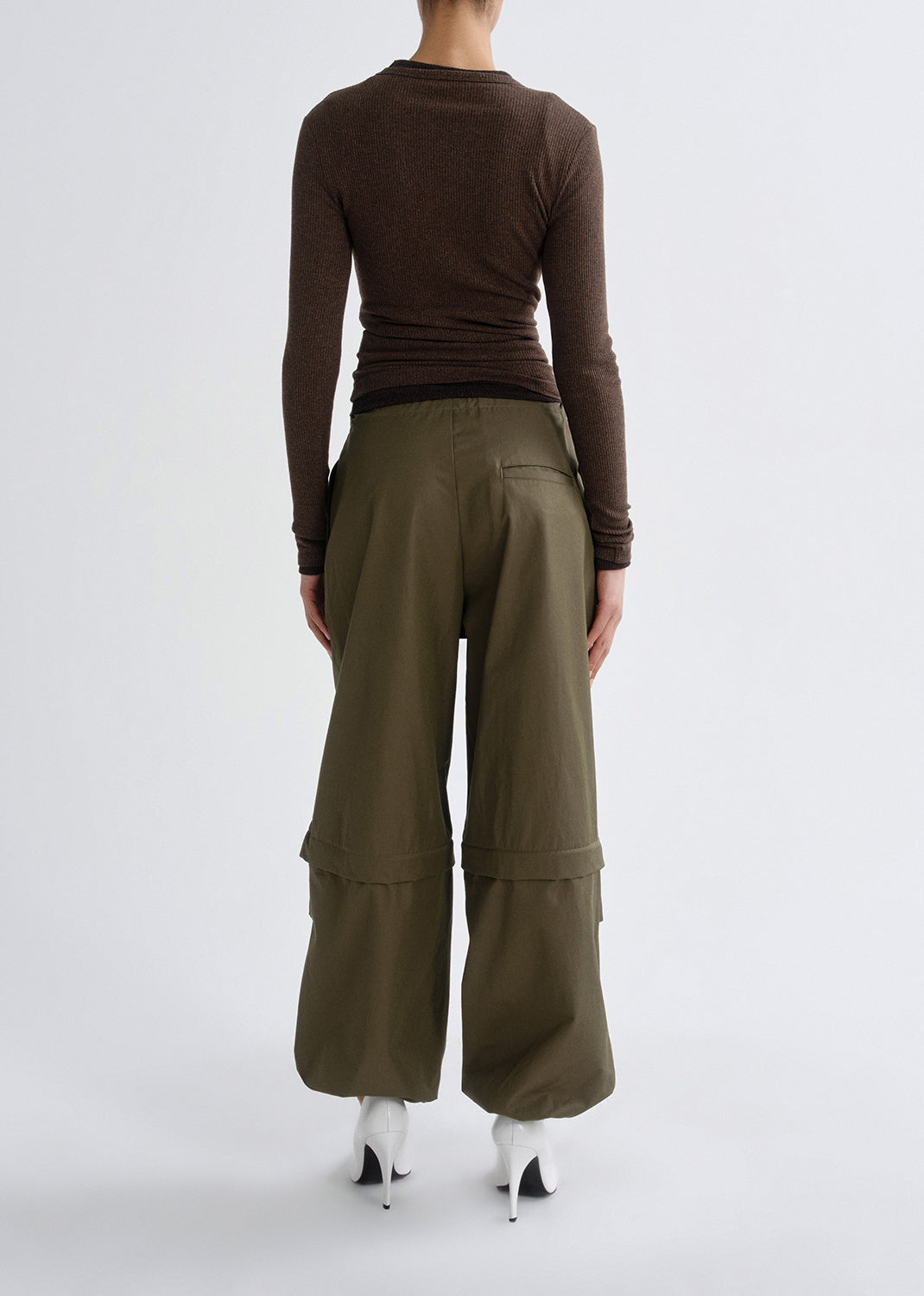 Person wearing a brown long-sleeve top and olive green wide-leg pants on a grey background