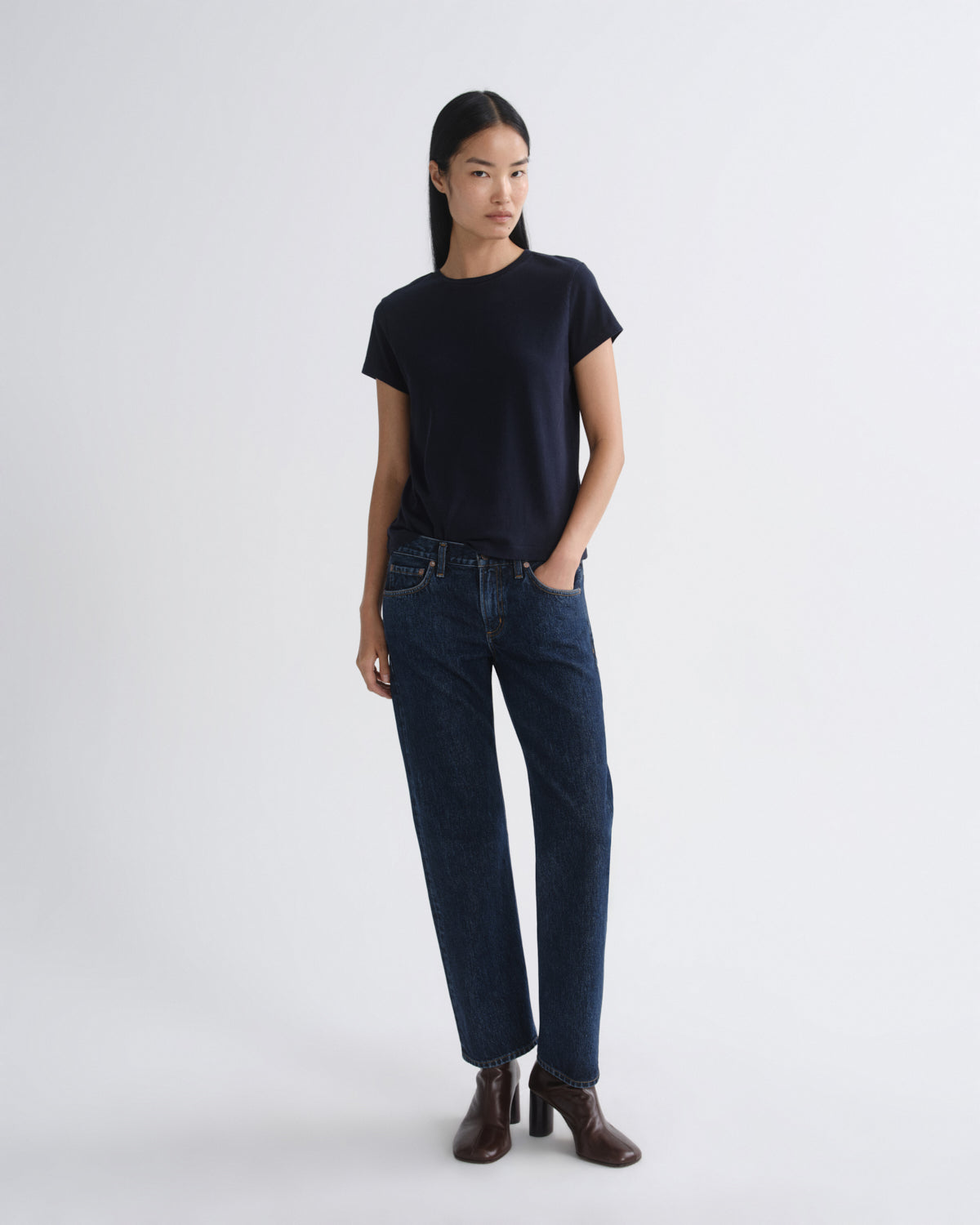 Woman wearing a black t-shirt and dark blue jeans on a white background